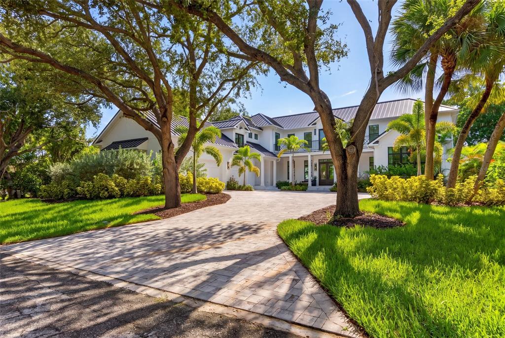 A two-story white house with a metal roof and a paved driveway surrounded by trees — 656 TROPICAL CIRCLE, SARASOTA, FL