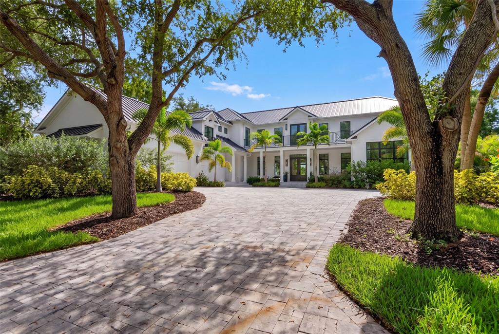A large white two-story house with a metal roof and a paved circular driveway — 656 TROPICAL CIRCLE, SARASOTA, FL