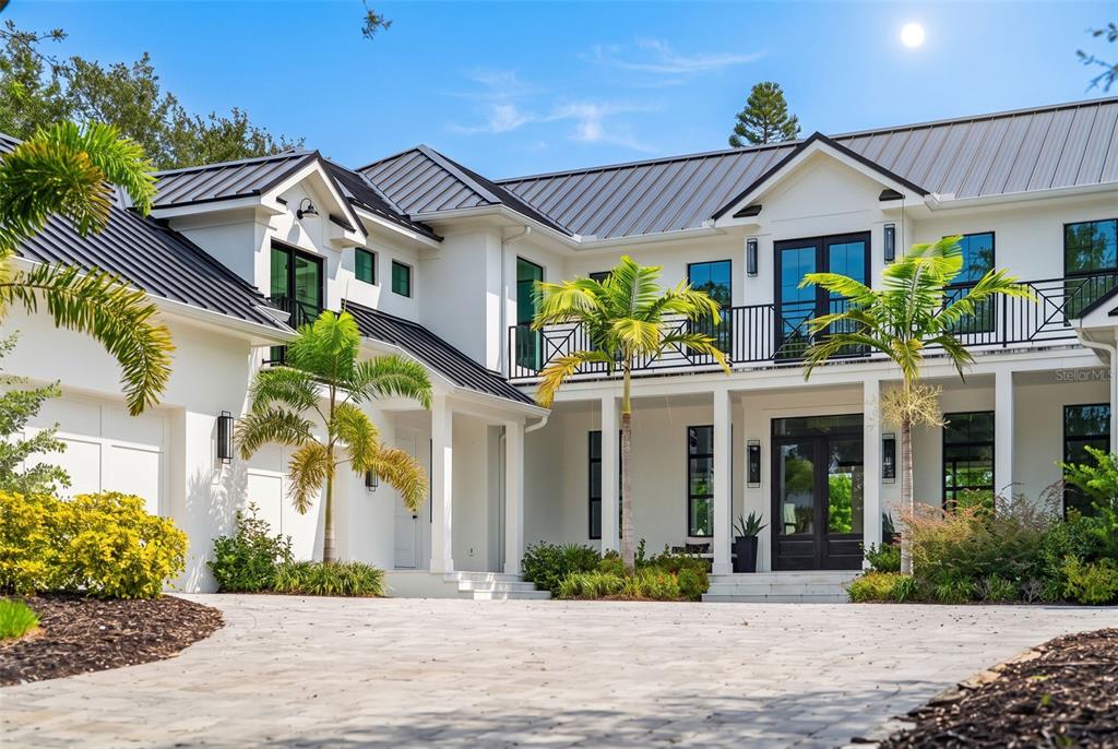 A two-story white house with a dark metal roof, palm trees, and a paved driveway — 656 TROPICAL CIRCLE, SARASOTA, FL