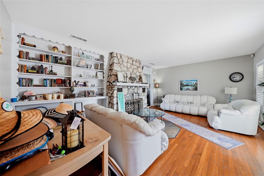 A living room features a stone fireplace, built-in white shelving, and white leather furniture — 726 MANDALAY AVENUE, CLEARWATER BEACH, FL