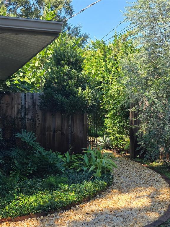 A gravel path winds through a lush garden toward a wooden fence and gate — 4718 CRYSTAL AVENUE, SARASOTA, FL