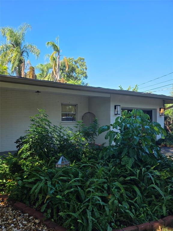 A white brick house exterior features a front garden with ferns and a hanging chair — 4718 CRYSTAL AVENUE, SARASOTA, FL