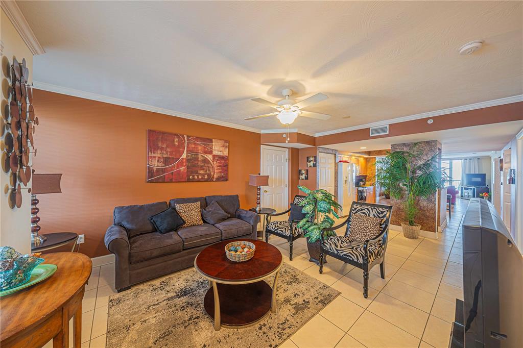 A living room features a dark sofa, patterned armchairs, a round coffee table, and tile flooring — 3315 S ATLANTIC AVENUE UNIT 1707, DAYTONA BEACH SHORES, FL