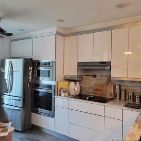 A modern kitchen features white cabinets, stainless steel appliances, and a wood-look backsplash — 9335 NW 45th Street # 9335, Sunrise FL 33351, SUNRISE, FL