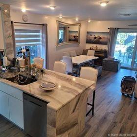 A kitchen with a stone-topped island and dining area featuring a large wall mirror — 9335 NW 45th Street # 9335, Sunrise FL 33351, SUNRISE, FL