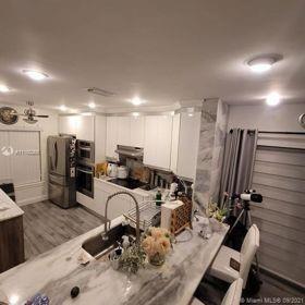 A kitchen features white cabinetry, stainless steel appliances, and a marble-topped island with a sink — 9335 NW 45th Street # 9335, Sunrise FL 33351, SUNRISE, FL