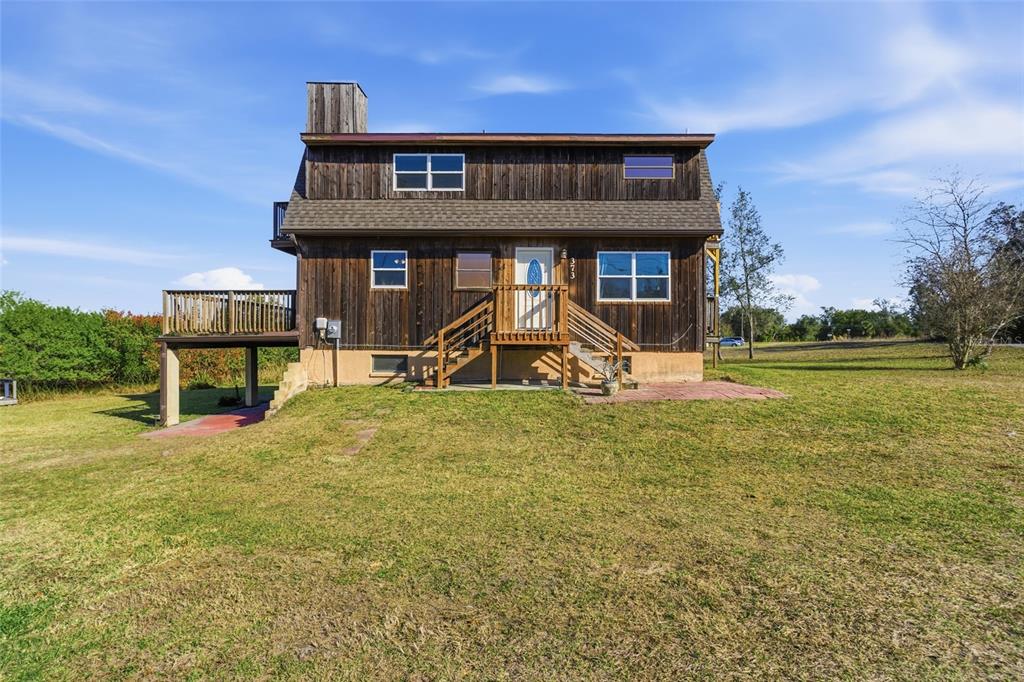 A two-story wooden house features a raised deck, a front staircase, and a chimney — 373 HILE LANE, PUNTA GORDA, FL