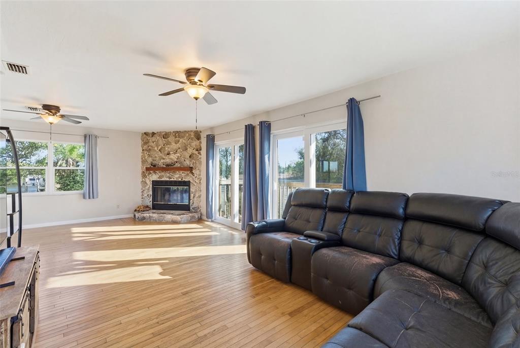 A living room features hardwood floors, a stone corner fireplace, and a black leather sofa — 373 HILE LANE, PUNTA GORDA, FL