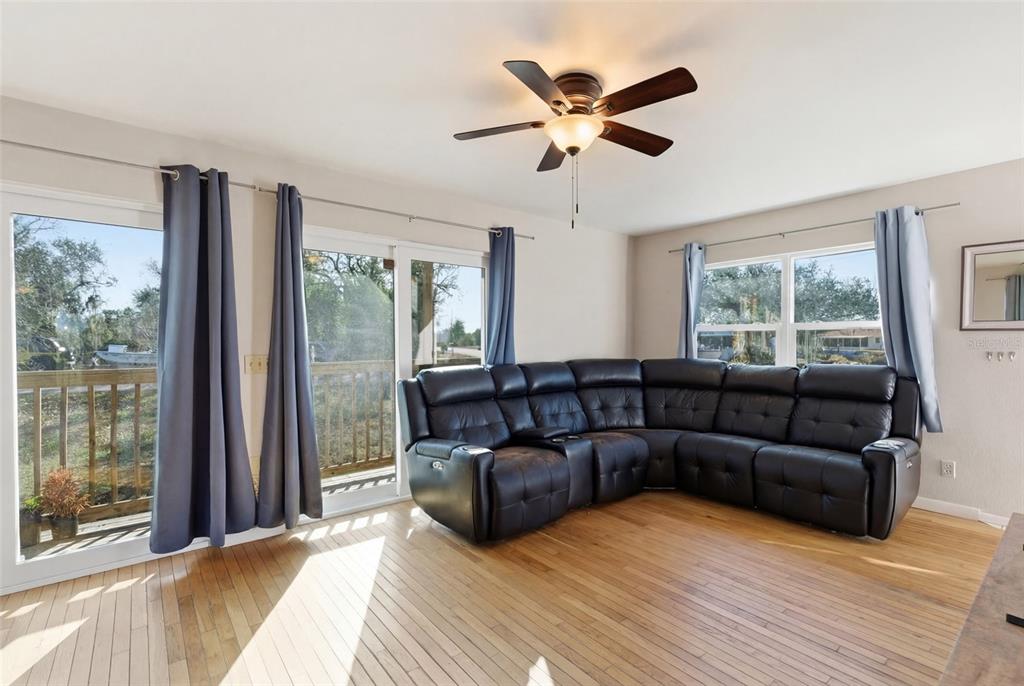 A living room with hardwood floors, a large black sectional sofa, and sliding glass doors — 373 HILE LANE, PUNTA GORDA, FL