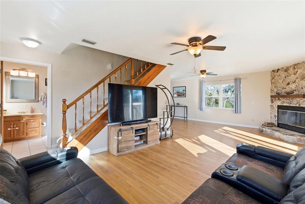 A living room features hardwood floors, a stone fireplace, a staircase, and a television console — 373 HILE LANE, PUNTA GORDA, FL