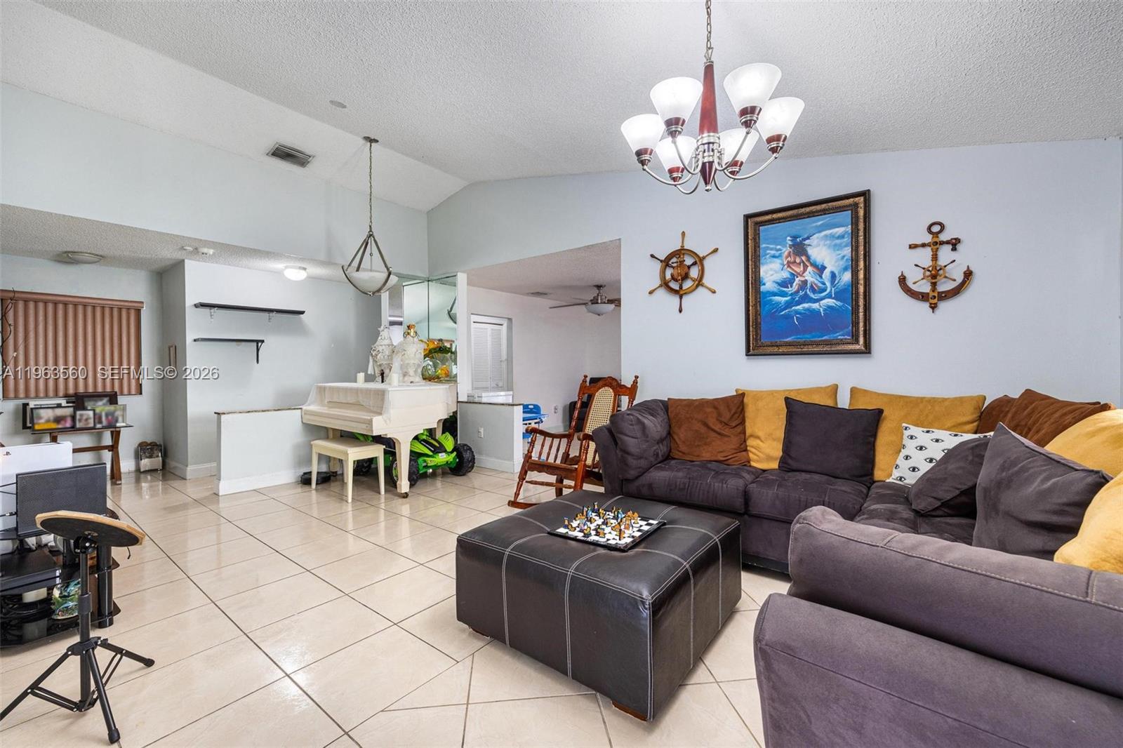 A living room features tile flooring, a sectional sofa, a piano, and nautical wall decor — 14217 SW 102nd St, Miami FL 33186, MIAMI, FL