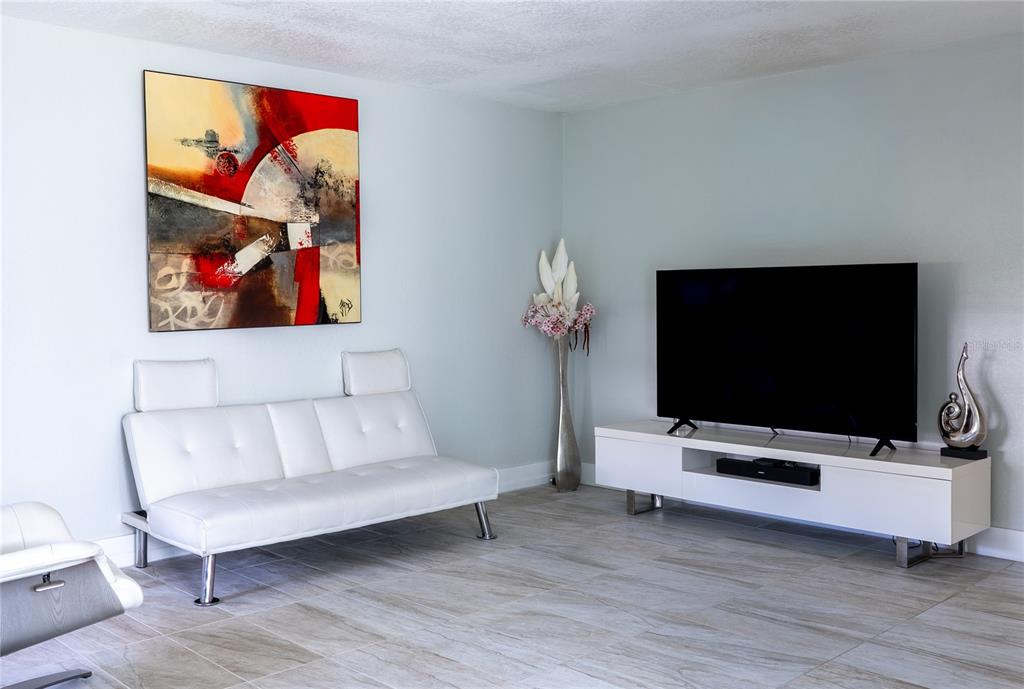 A living room features a white sofa, a television on a stand, and abstract wall art — 592 FANSHAW O UNIT 592-O, BOCA RATON, FL