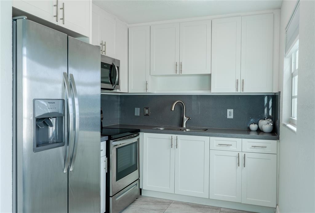A kitchen features white cabinets, stainless steel appliances, and a dark gray countertop — 592 FANSHAW O UNIT 592-O, BOCA RATON, FL