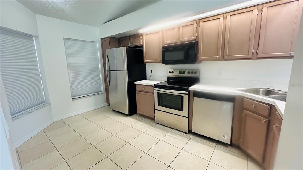 An empty room with light-colored tile flooring, high ceilings, and sliding glass doors — 12121 AUGUSTA WOODS CIRCLE, ORLANDO, FL
