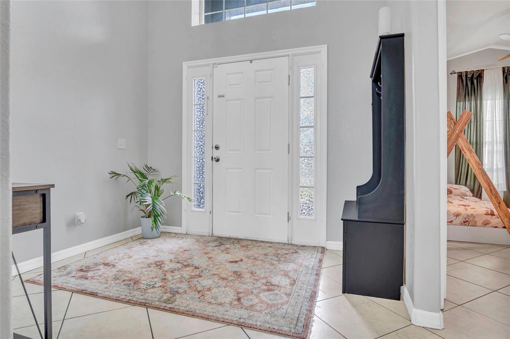 An entryway features a white front door with sidelights, a patterned area rug, and tile flooring — 8335 ADELE ROAD, LAKELAND, FL