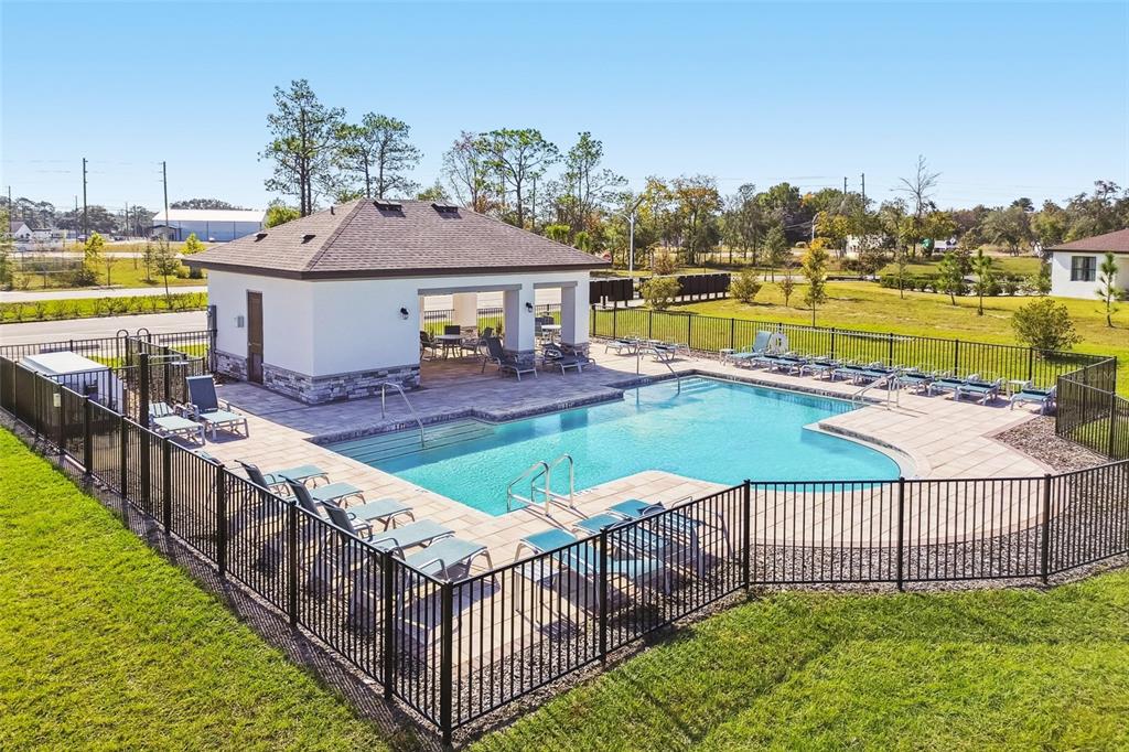 An outdoor swimming pool with a covered patio and lounge chairs enclosed by a fence — 133 NORTHBANK LANE, SPRING HILL, FL