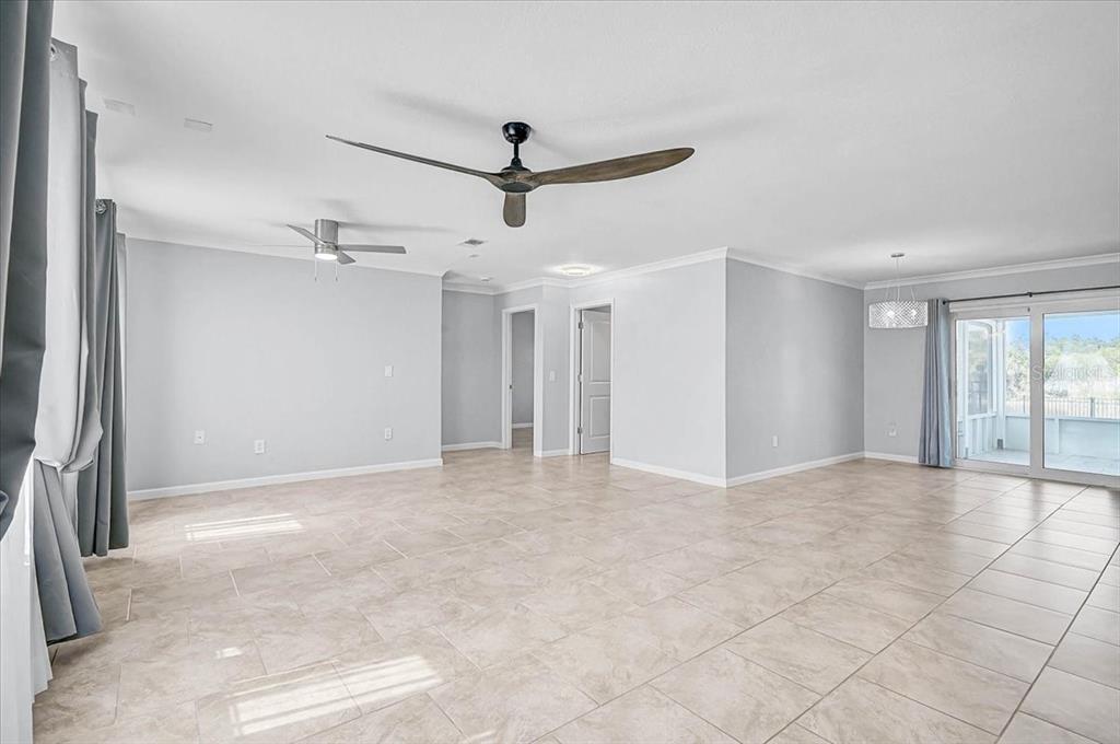 A spacious, light-filled living area features tile flooring, two ceiling fans, and sliding glass doors — 6652 THORMAN ROAD, PORT CHARLOTTE, FL