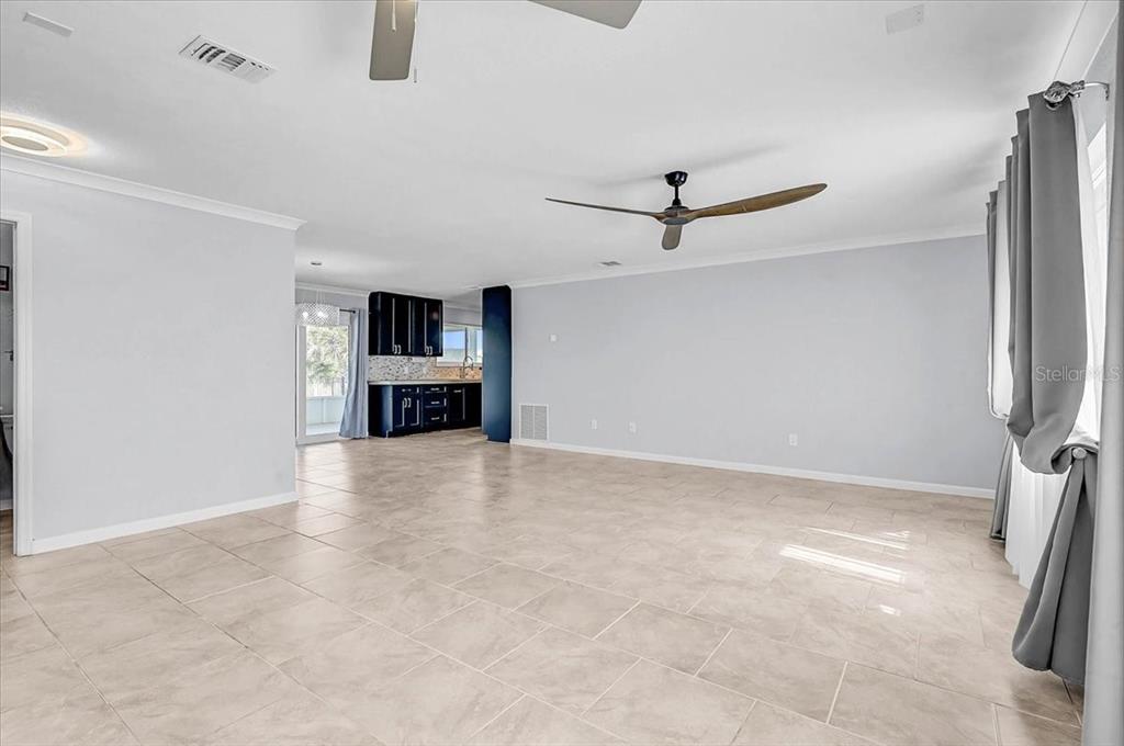 A spacious living area with tile flooring, a ceiling fan, and an open kitchen — 6652 THORMAN ROAD, PORT CHARLOTTE, FL