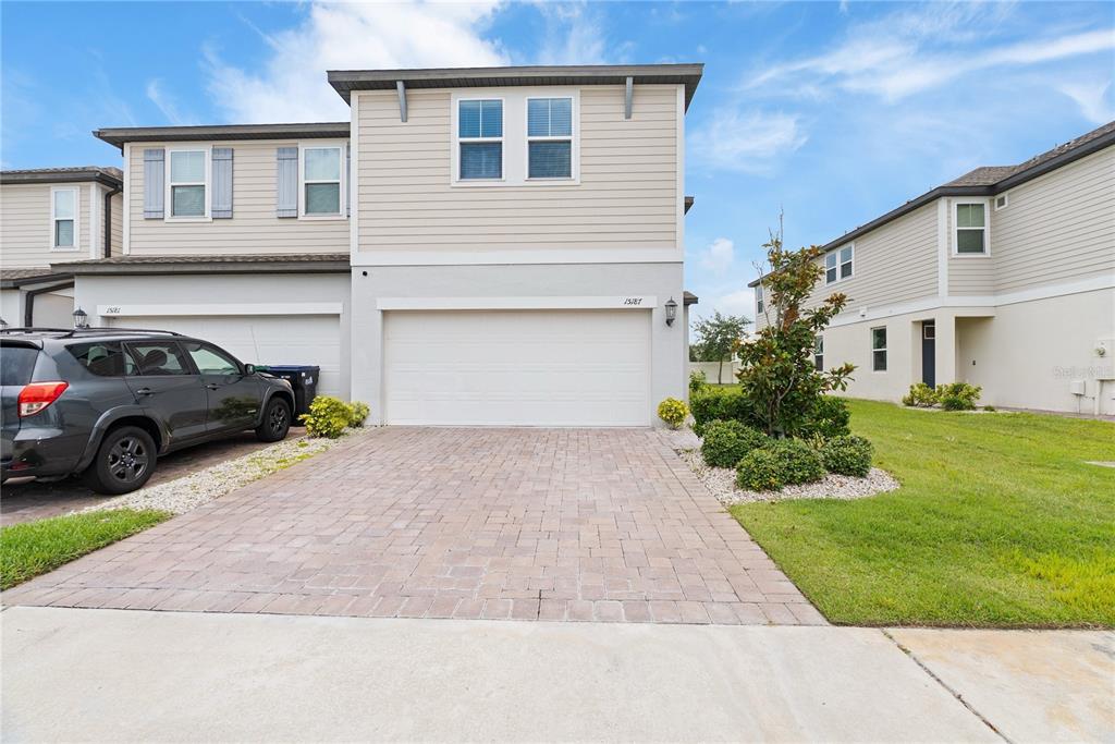 A two-story townhouse with a beige exterior, a single-car garage, and a small front yard — 15187 WILLOW ARBOR CIRCLE, ORLANDO, FL