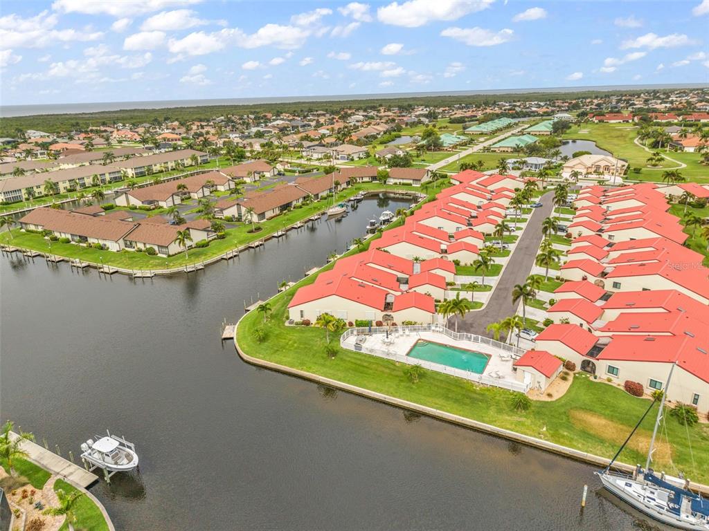 A palm tree stands on a grassy lawn overlooking a canal lined with houses — 3830 BAL HARBOR BOULEVARD UNIT #15, PUNTA GORDA, FL