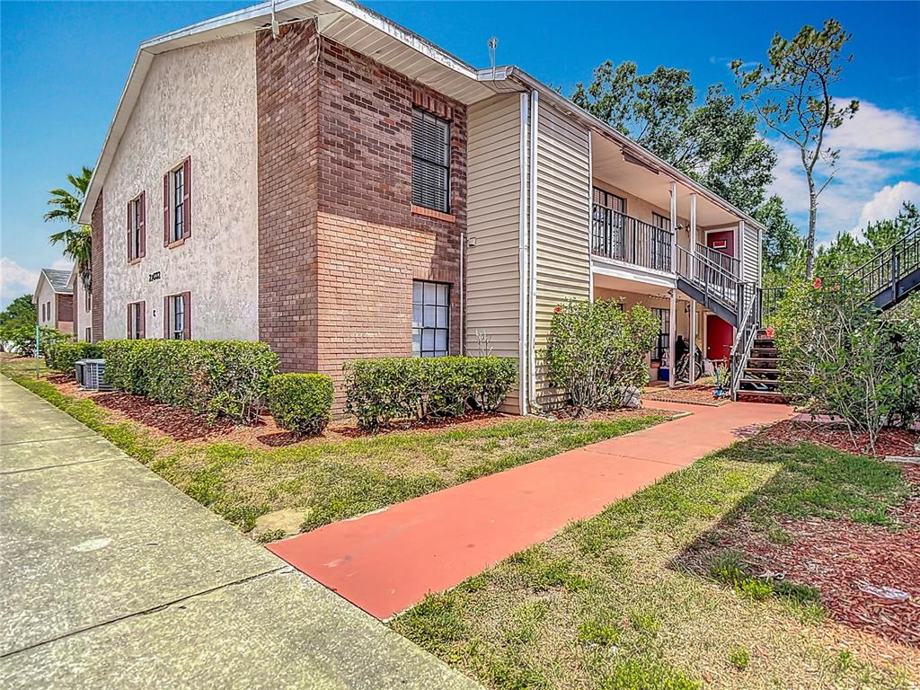 A two-story apartment building with brick and siding exterior, a balcony, and an outdoor staircase — 21032 VOYAGER BLVD UNIT 8, LAND O LAKES, FL