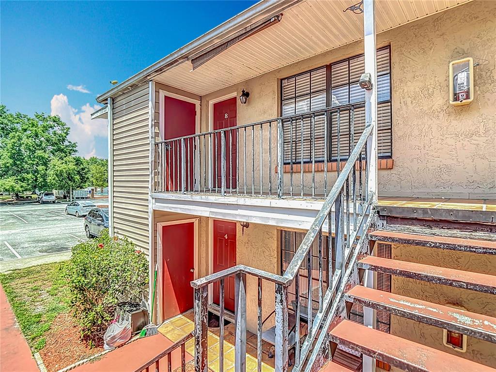 An exterior view of a two-story apartment building with red doors and metal stairs — 21032 VOYAGER BLVD UNIT 8, LAND O LAKES, FL