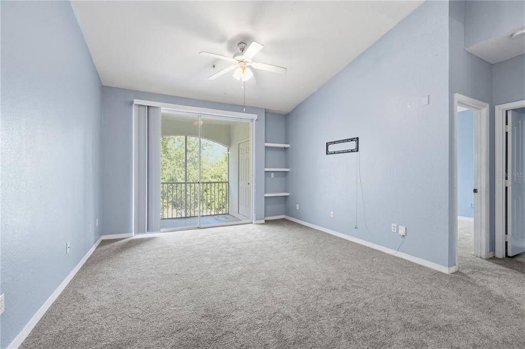 A carpeted living room with light blue walls, a ceiling fan, and a sliding glass door — 2525 MAITLAND CROSSING WAY UNIT 304, ORLANDO, FL