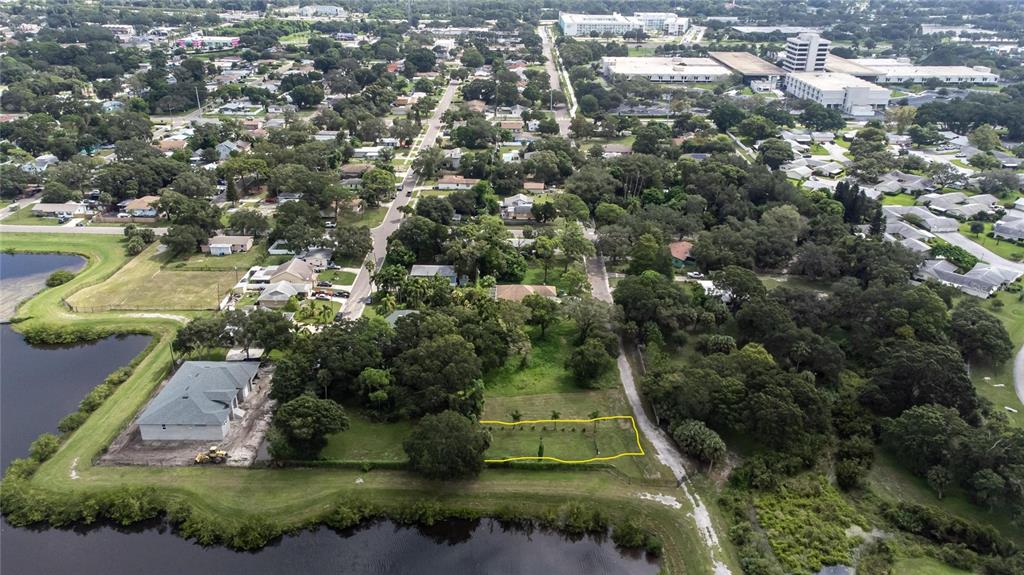 An aerial view shows a vacant, rectangular lot outlined in yellow near a lake — 3834 29 AVENUE, ST PETERSBURG, FL