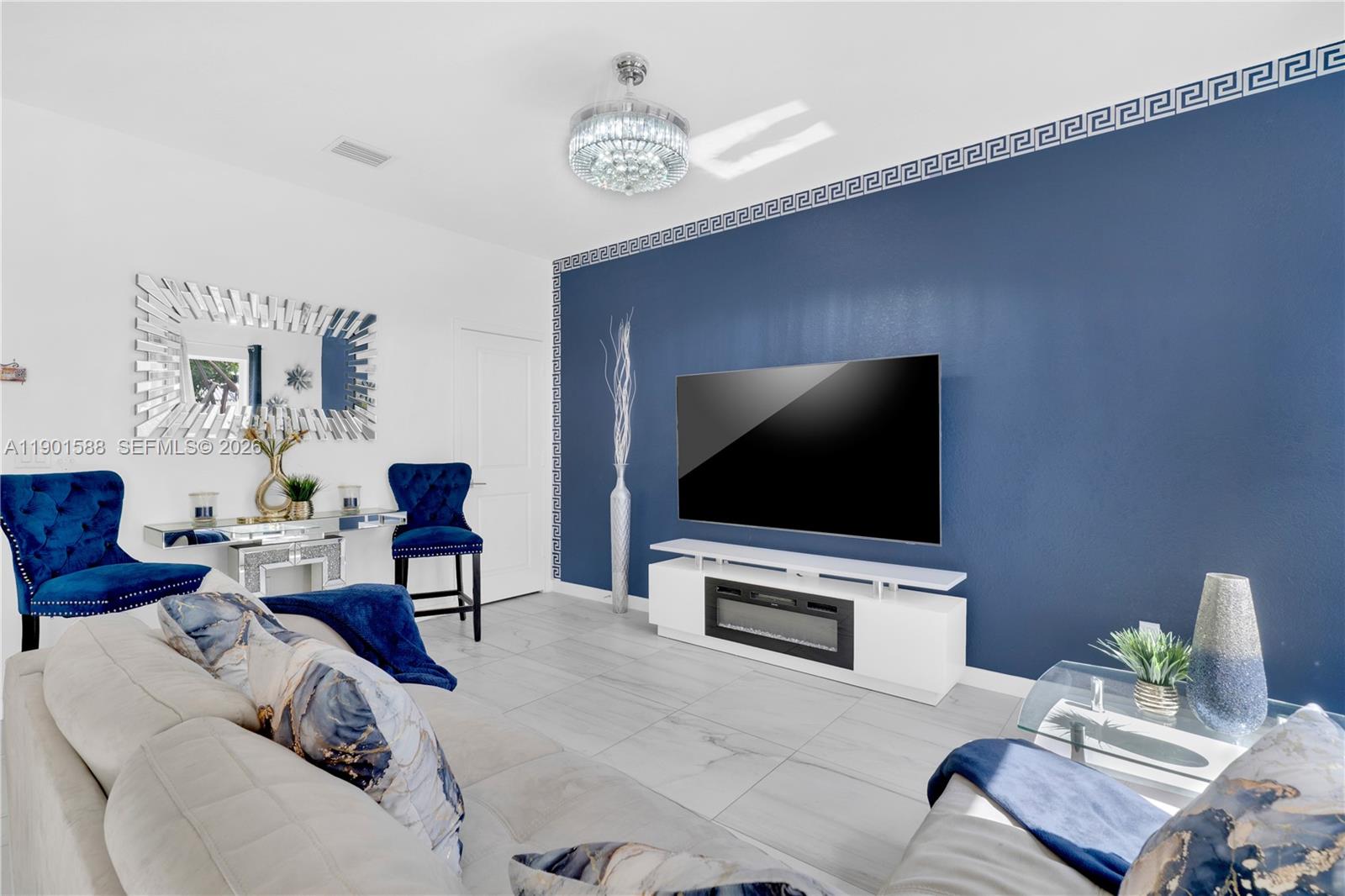 A living room features a blue accent wall with a Greek key border and television — 856 SE 16th Ct, Homestead FL 33034, HOMESTEAD, FL