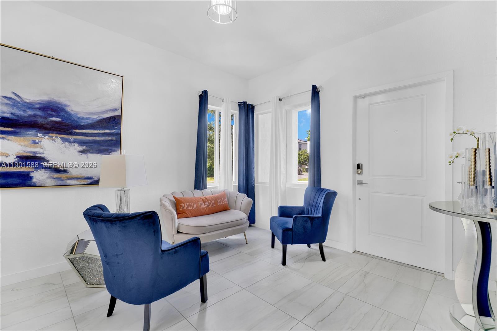 A bright living area features white walls, tiled floors, blue velvet chairs, and a sofa — 856 SE 16th Ct, Homestead FL 33034, HOMESTEAD, FL