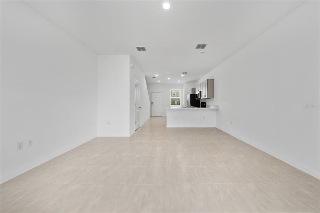 An open-concept living area features light-colored tile flooring, white walls, and a kitchen island — 2916 SKYLINE LOOP, KISSIMMEE, FL