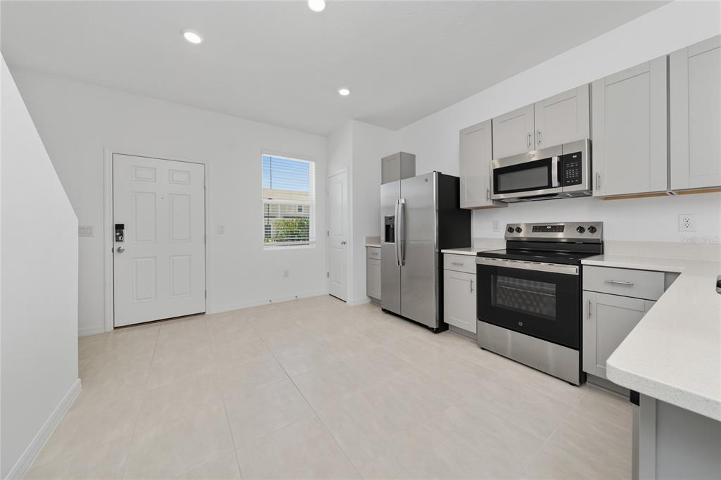 A kitchen with light gray cabinets, stainless steel appliances, and white tile flooring — 2916 SKYLINE LOOP, KISSIMMEE, FL