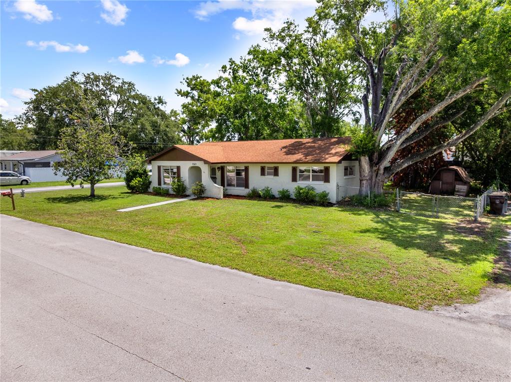 A single-story house with a brown roof and white siding sits on a grassy lot — 1501 VIRGINIA AVENUE, ST CLOUD, FL