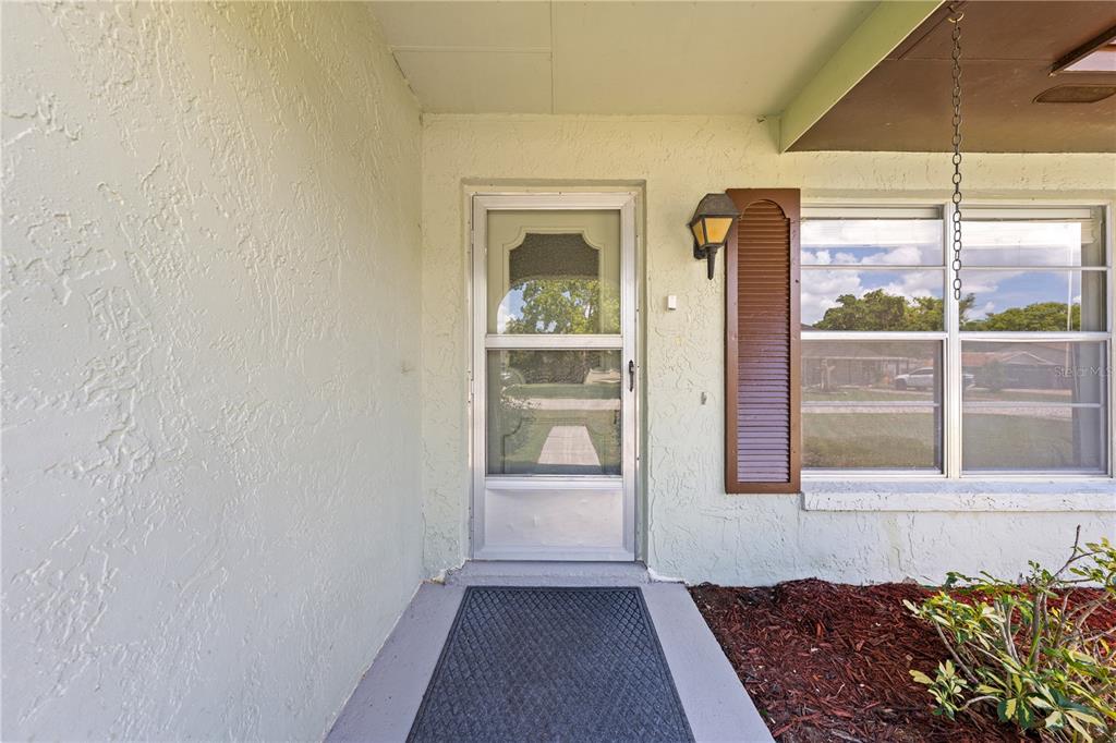 A front porch with a storm door, a single shutter, and a window — 1501 VIRGINIA AVENUE, ST CLOUD, FL
