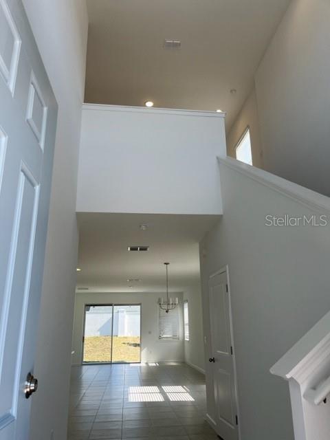 An entryway with a high ceiling, tiled floors, a staircase, and a view of the backyard — 4502 DAVOS DRIVE, CLERMONT, FL