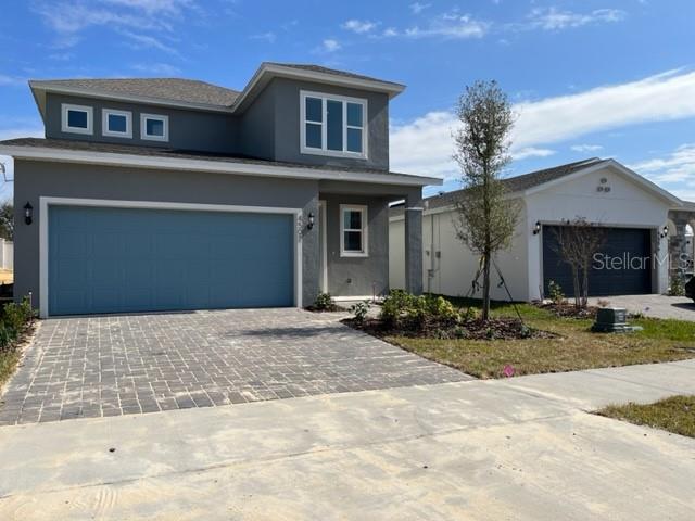A two-story gray house with a blue garage door and a neighboring single-story garage — 4502 DAVOS DRIVE, CLERMONT, FL