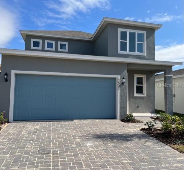 A two-story house with a gray exterior, a blue garage door, and a paved driveway — 4502 DAVOS DRIVE, CLERMONT, FL