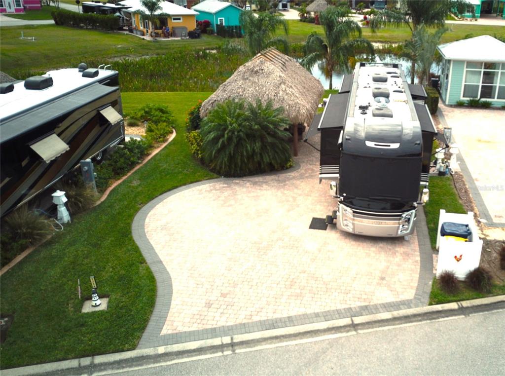 An aerial view shows a paved driveway with a parked RV and a tiki hut — 3254 RED TAIL HAWK DRIVE, POLK CITY, FL