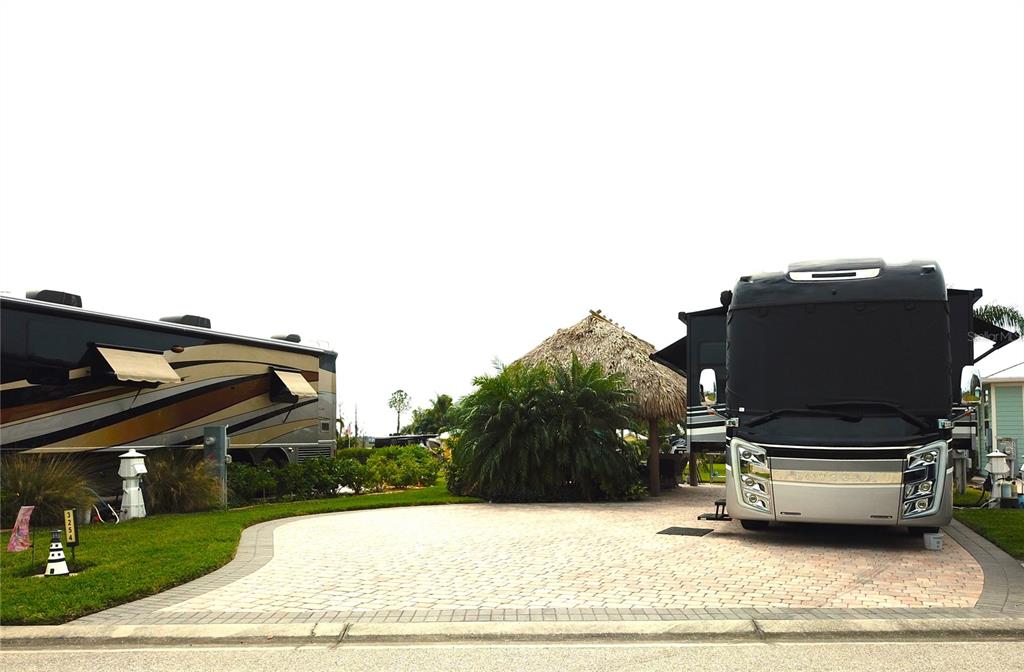 Two large recreational vehicles are parked on a paved lot with a tiki hut — 3254 RED TAIL HAWK DRIVE, POLK CITY, FL