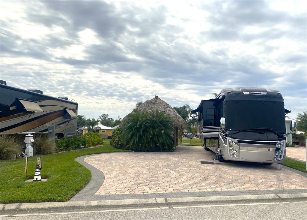 A paved driveway features a tiki hut between two large recreational vehicles — 3254 RED TAIL HAWK DRIVE, POLK CITY, FL