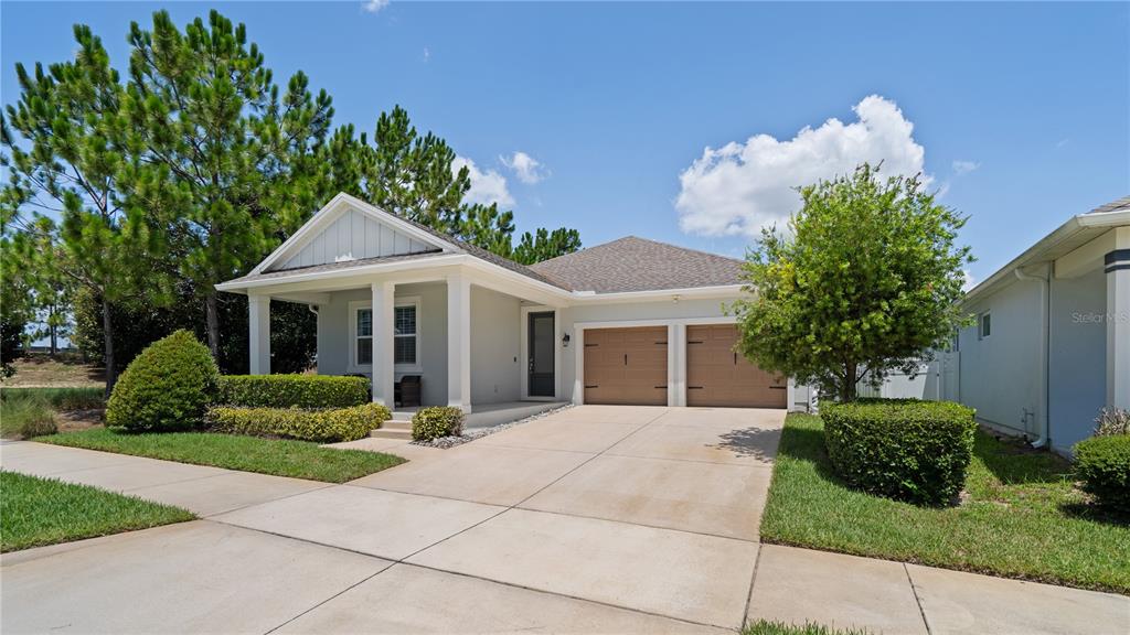 A single-story house with a light gray exterior, a front porch, and a two-car garage — 15395 SUGAR CITRUS DRIVE, WINTER GARDEN, FL