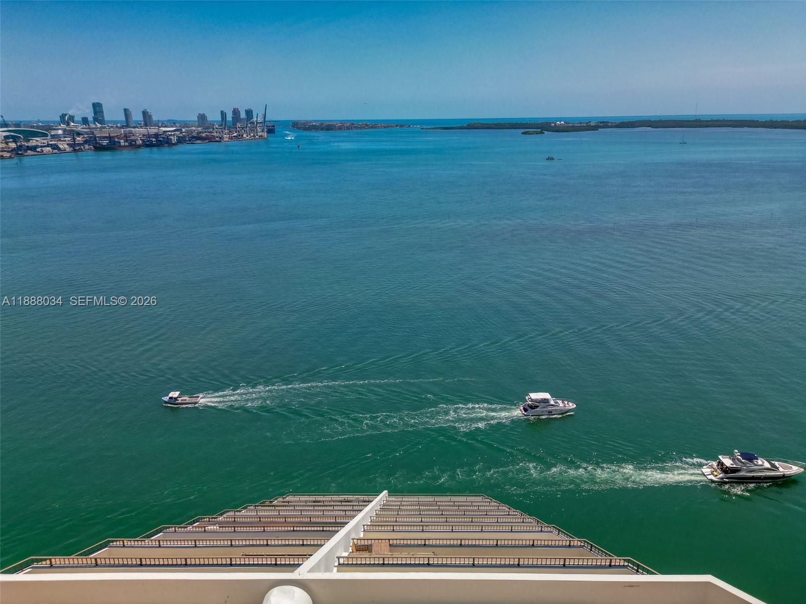 An aerial view of a balcony overlooking a bay with boats and a distant city skyline — 520 Brickell Key Drive # 03, Miami FL 33131, MIAMI, FL
