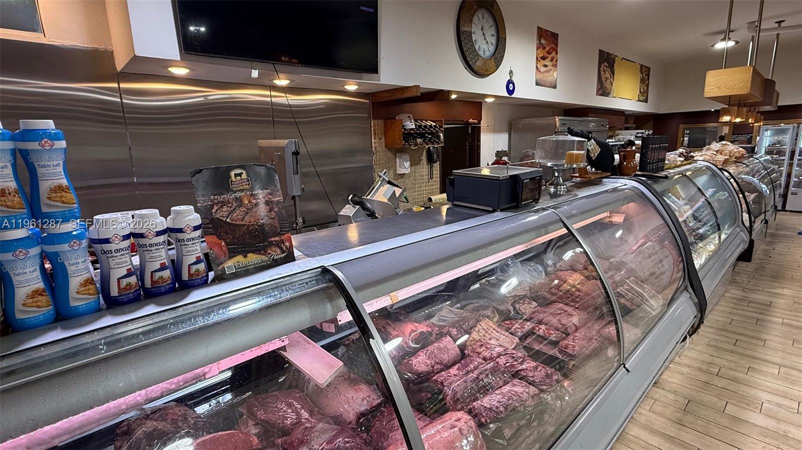 A butcher shop features a long refrigerated display case filled with various cuts of meat — 1305 SW 8th St, Miami FL 33135, MIAMI, FL