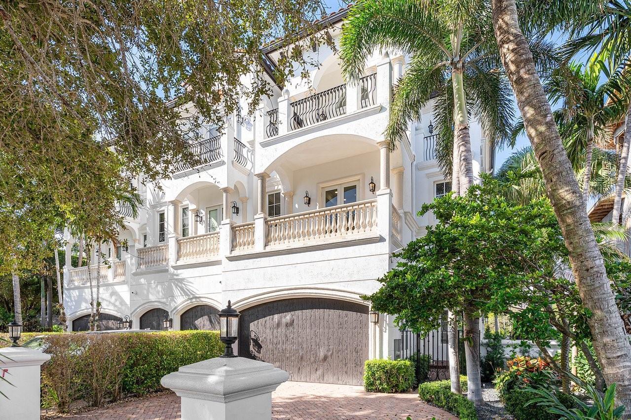 A multi-story white Mediterranean-style house features arched balconies, a stone-paved driveway, and lush landscaping — 549 NE 19th Avenue # C, Deerfield Beach FL 33441, DEERFIELD BEACH, FL