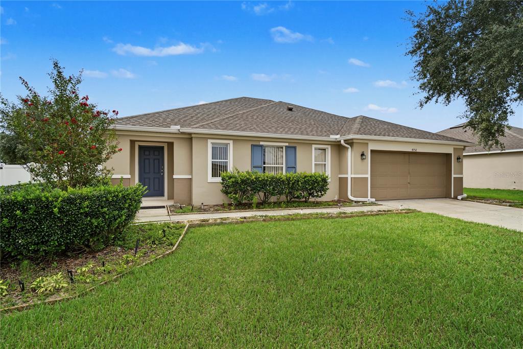 A single-story house with a tan exterior, a brown roof, and a two-car garage — 4752 BARBADOS LOOP, CLERMONT, FL