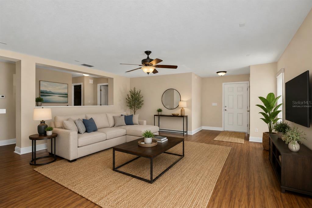 A living room features a beige sectional sofa, a dark coffee table, and wood-look flooring — 4752 BARBADOS LOOP, CLERMONT, FL