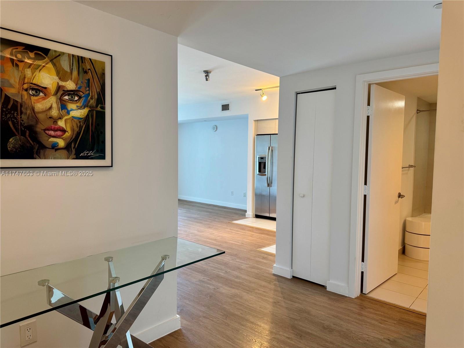 A hallway with a glass console table leads to a kitchen and a bathroom — 4250 Biscayne Blvd # 1006, Miami FL 33137, MIAMI, FL