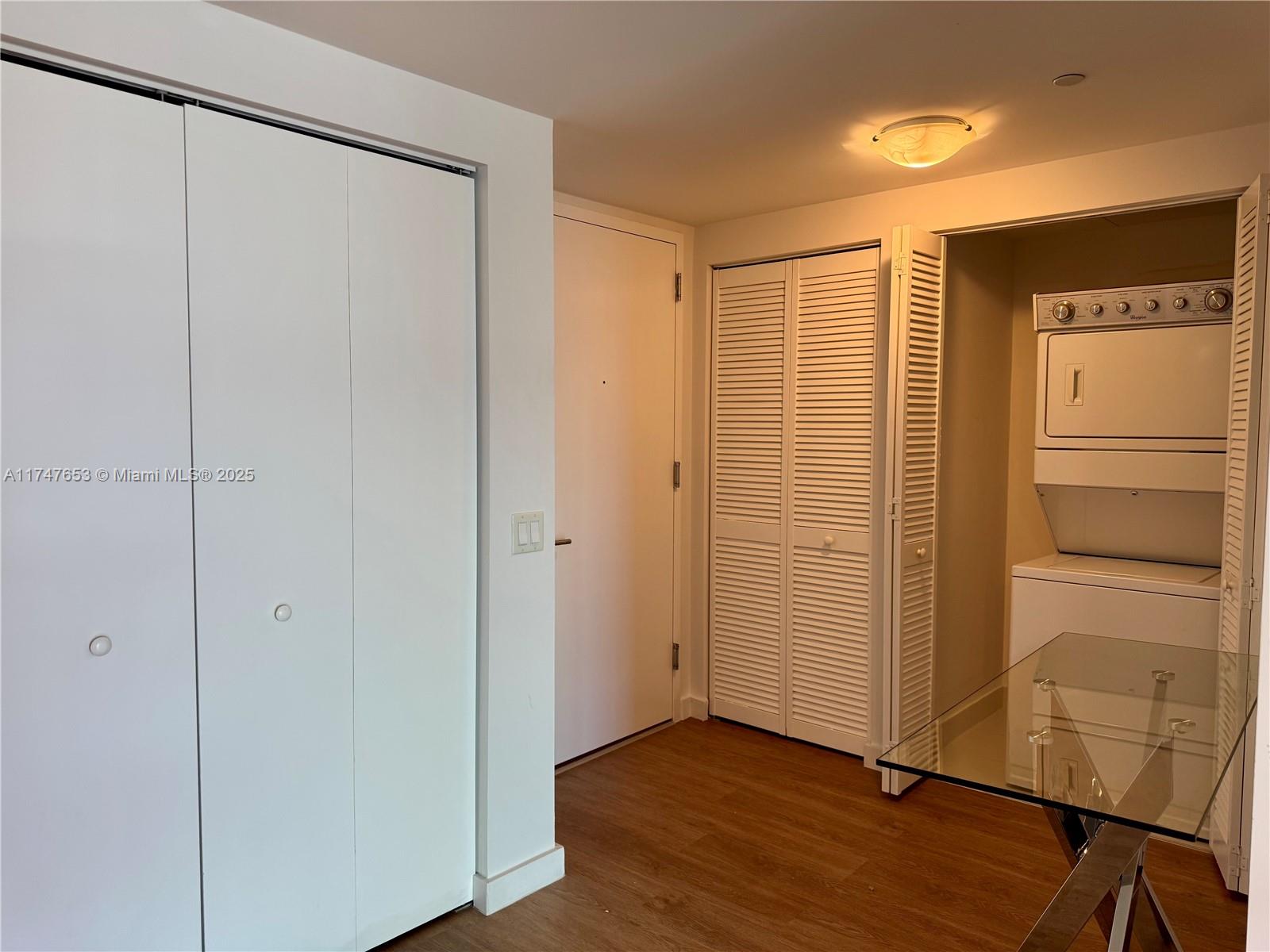 A room features wood-look flooring, white closet doors, a laundry closet, and a glass table — 4250 Biscayne Blvd # 1006, Miami FL 33137, MIAMI, FL
