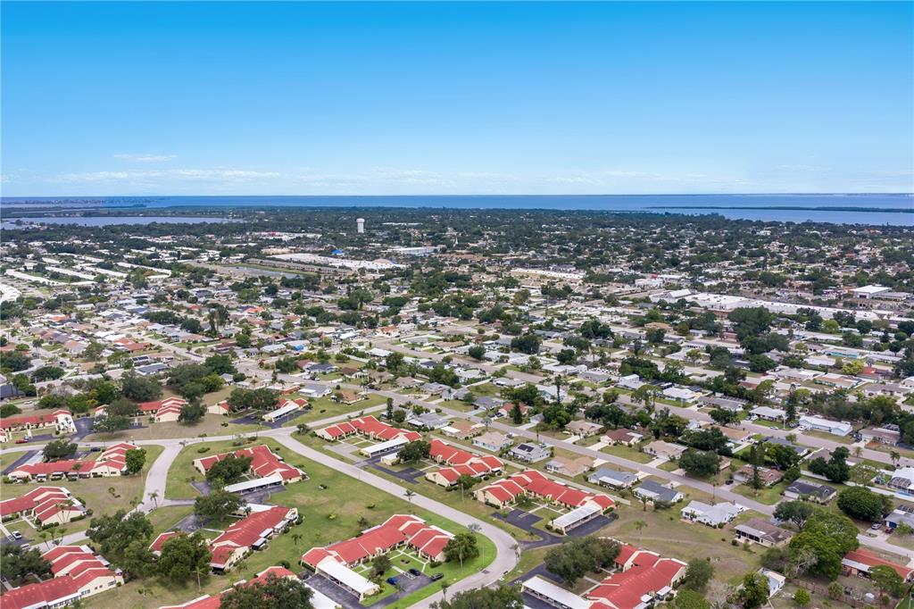 An aerial view shows a residential neighborhood with red-roofed buildings and a distant coastline — 1208 56TH STREET W UNIT 1208, BRADENTON, FL