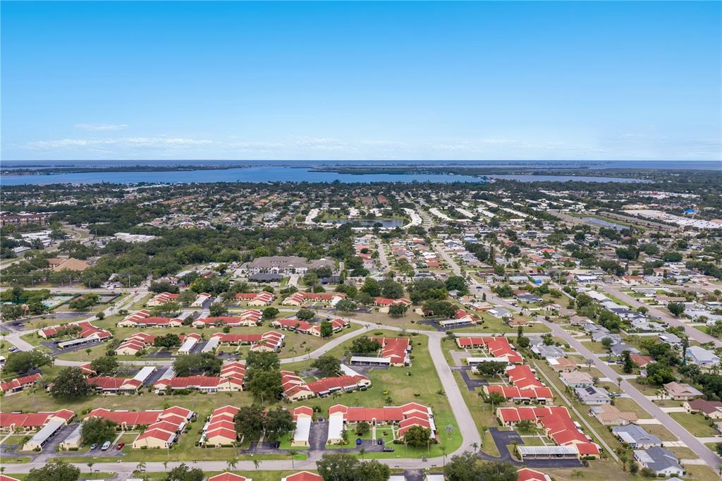 An aerial view shows a residential neighborhood with red-roofed buildings and a distant bay — 1208 56TH STREET W UNIT 1208, BRADENTON, FL